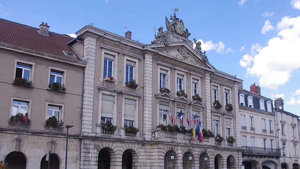 Façade de l'hôtel de ville de Pont-à-Mousson ornée de drapeaux français et européens, sous un ciel bleu