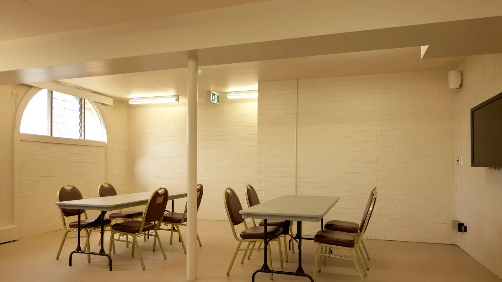 Salle de réunion municipale vide avec tables, chaises et écran mural, sous une mairie
