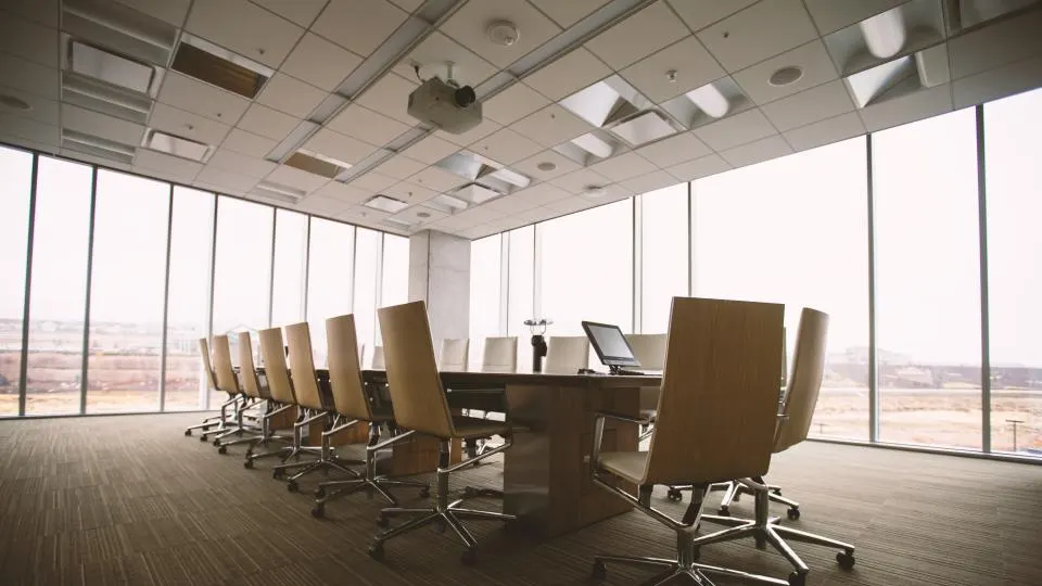 Salle de réunion vide avec grande table, fauteuils et baies vitrées